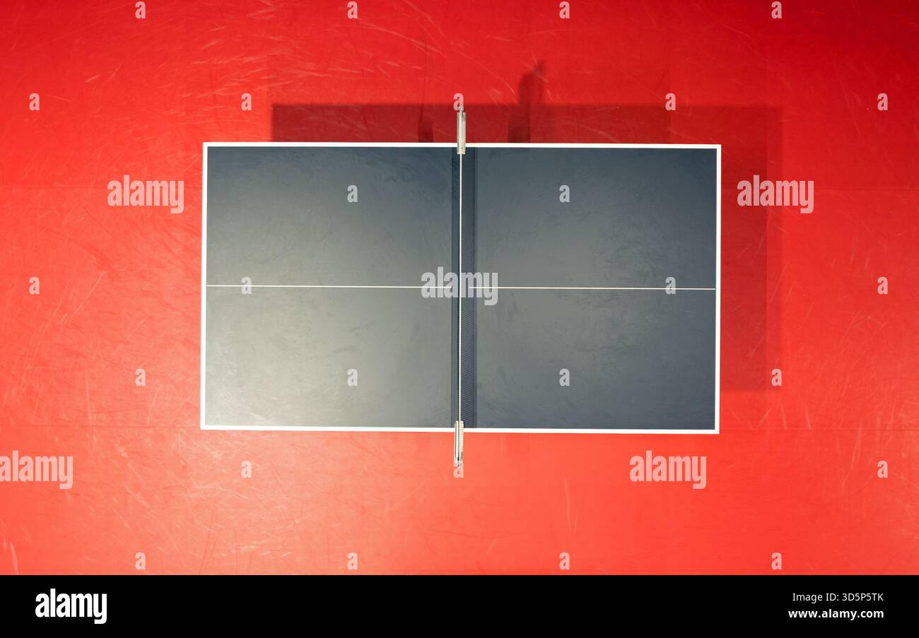 Schwarze Tischtennis- oder Tischtennisplatte befindet sich auf einem roten, orangen Boden des Hallenstadions für Wettbewerbe Turniere Stockfoto