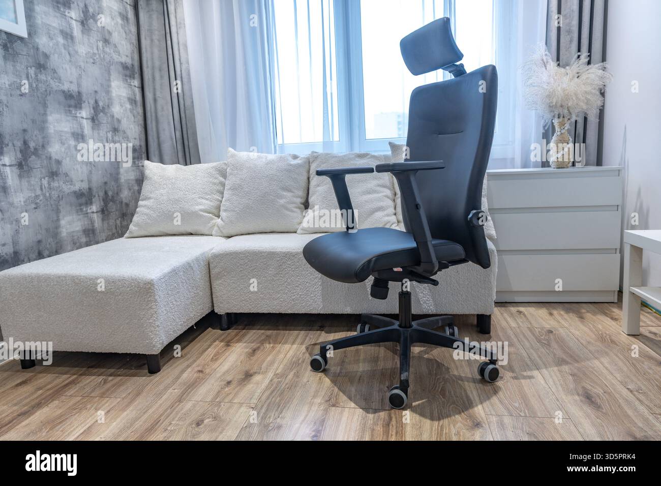 Ein schwarzer Drehstuhl aus Leder mit höhenverstellbarer Kopfstütze in einem modernen Büro eines Geschäftsmannes. Stockfoto