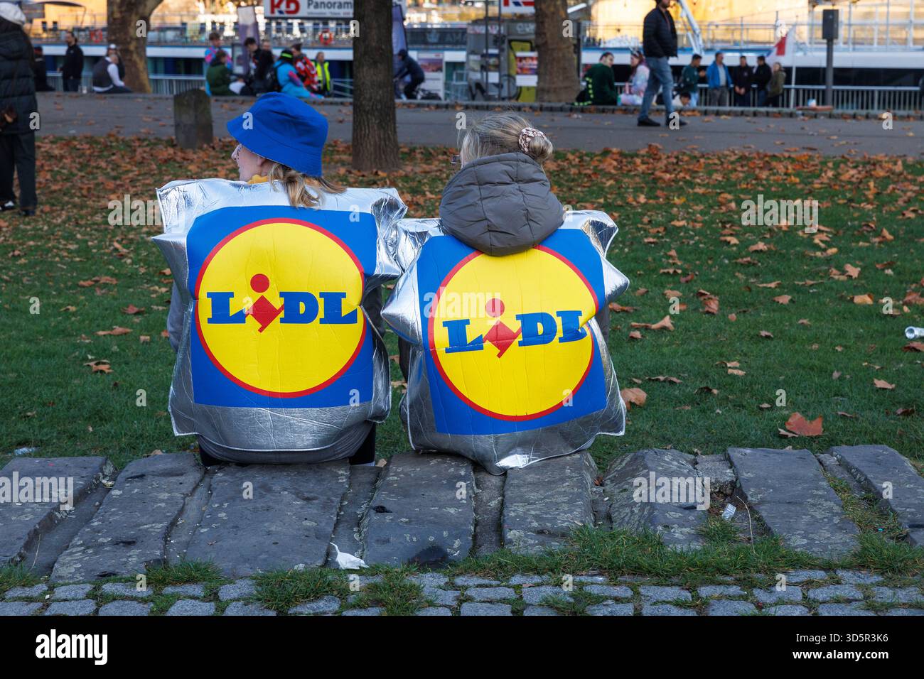 Am Tag der Eröffnung der Karnevalsveranstaltung am 11.11.25 feiern viele Menschen im Rheingarten in der Altstadt Lidl-Tasche als Karnevalskostüm Stockfoto