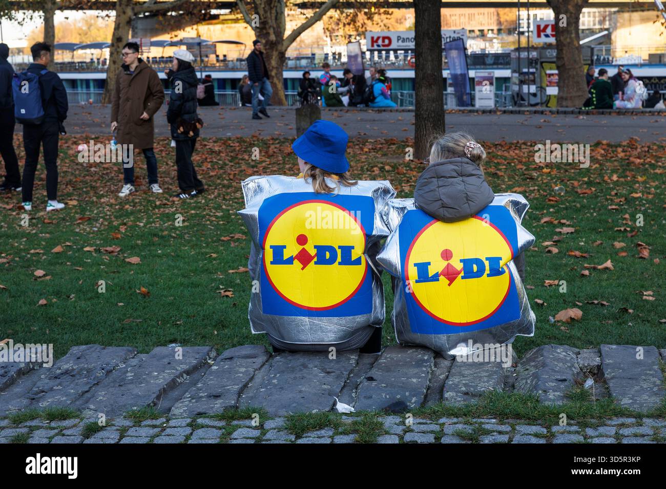 Am Tag der Eröffnung der Karnevalsveranstaltung am 11.11.25 feiern viele Menschen im Rheingarten in der Altstadt Lidl-Tasche als Karnevalskostüm Stockfoto