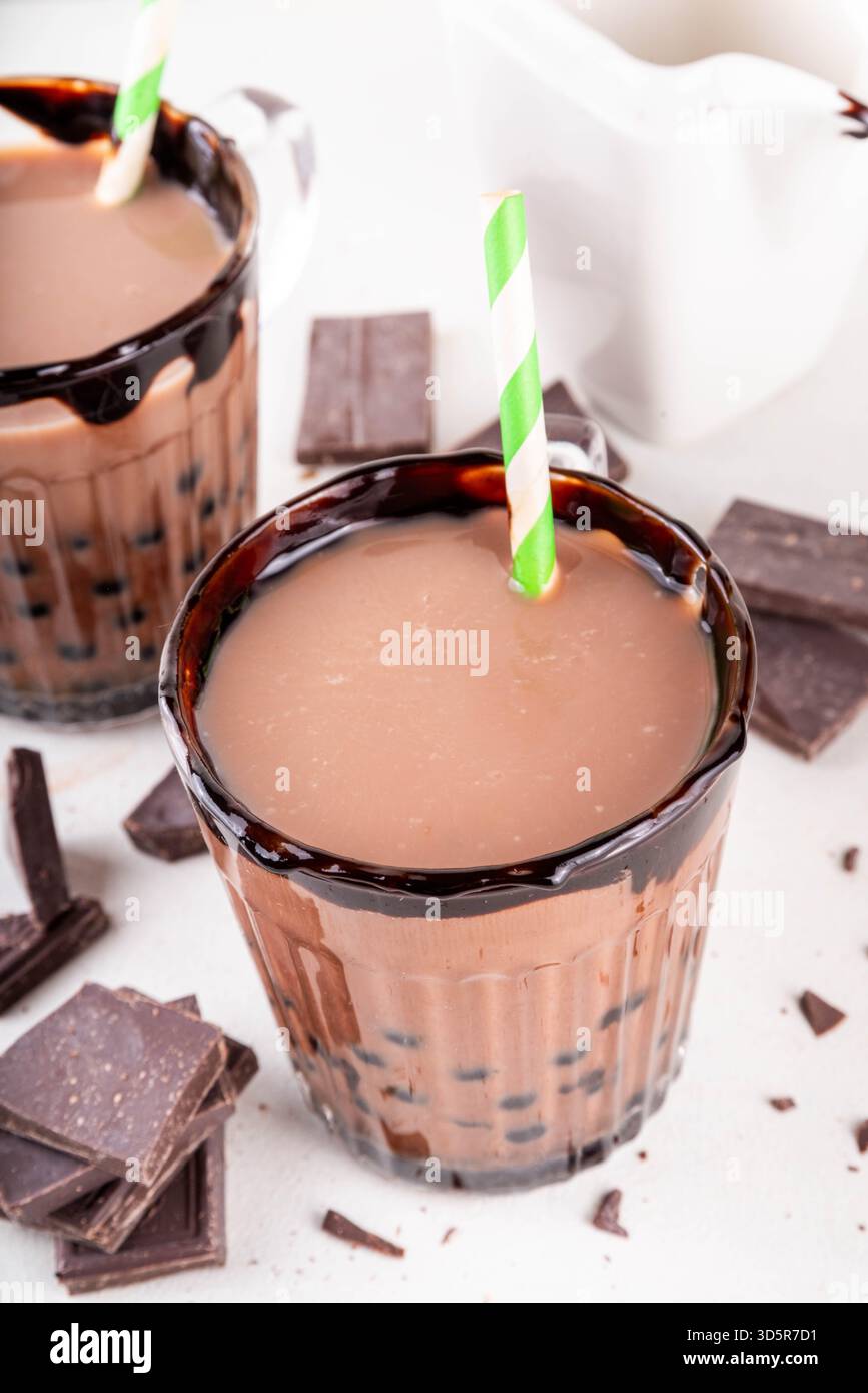 Leckerer heißer Schokoladen-Bubble-Tee. Kakao warm- oder kaltgetränk mit Tapiokakugeln und dunklem Schokoladensirup, süßes Dessertgetränk auf weißem Tisch mit c Stockfoto
