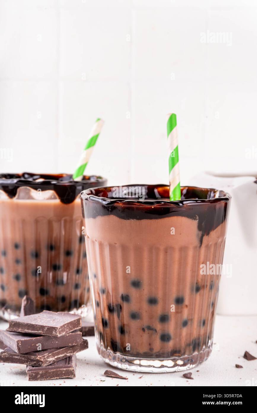 Leckerer heißer Schokoladen-Bubble-Tee. Kakao warm- oder kaltgetränk mit Tapiokakugeln und dunklem Schokoladensirup, süßes Dessertgetränk auf weißem Tisch mit c Stockfoto
