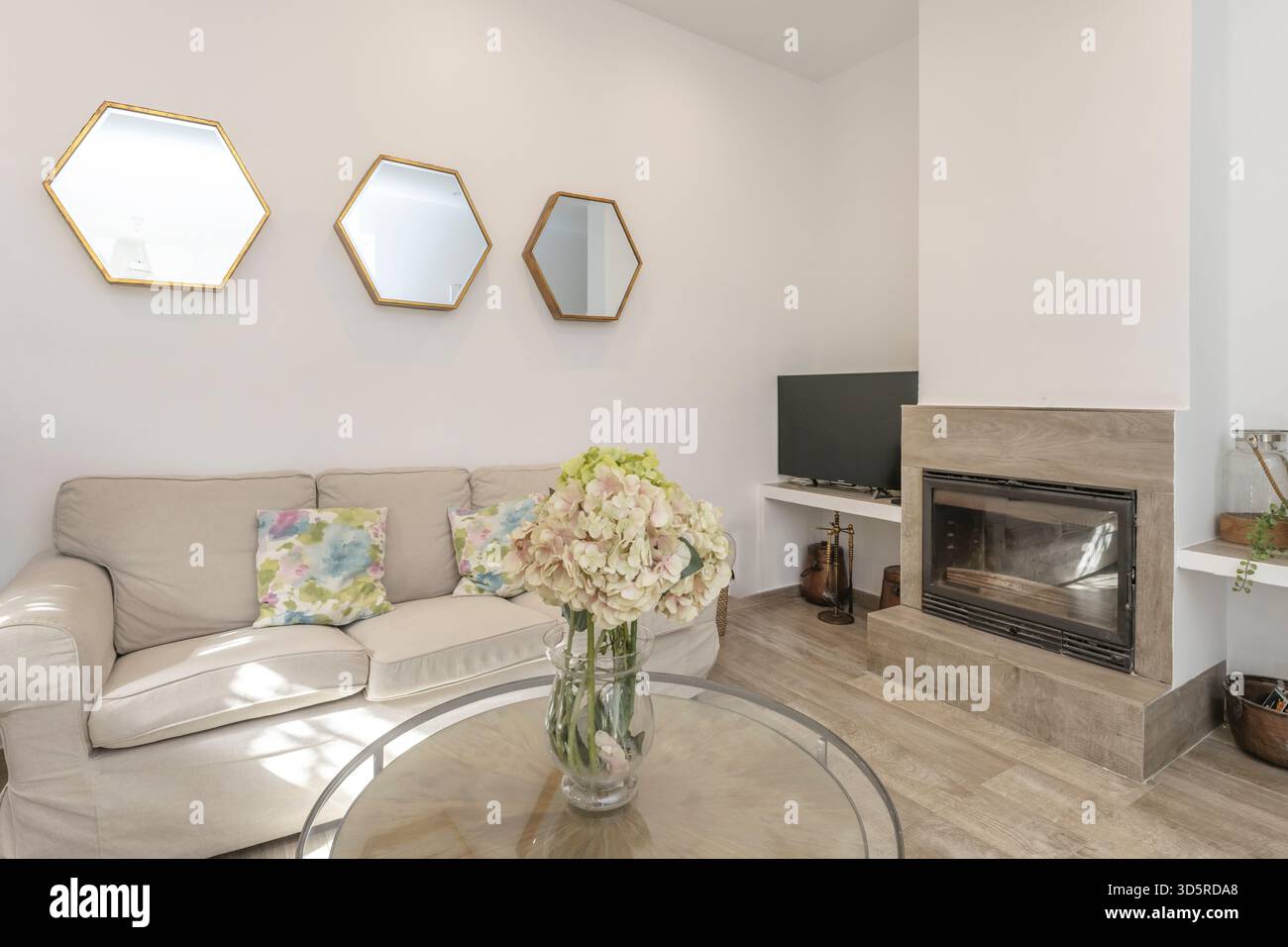 Vorderansicht eines modernen Wohnzimmers mit eingebautem Gaskamin und weißer Marmorverkleidung, integriert in die TV-Wand mit eingebauten Regalen. Stockfoto