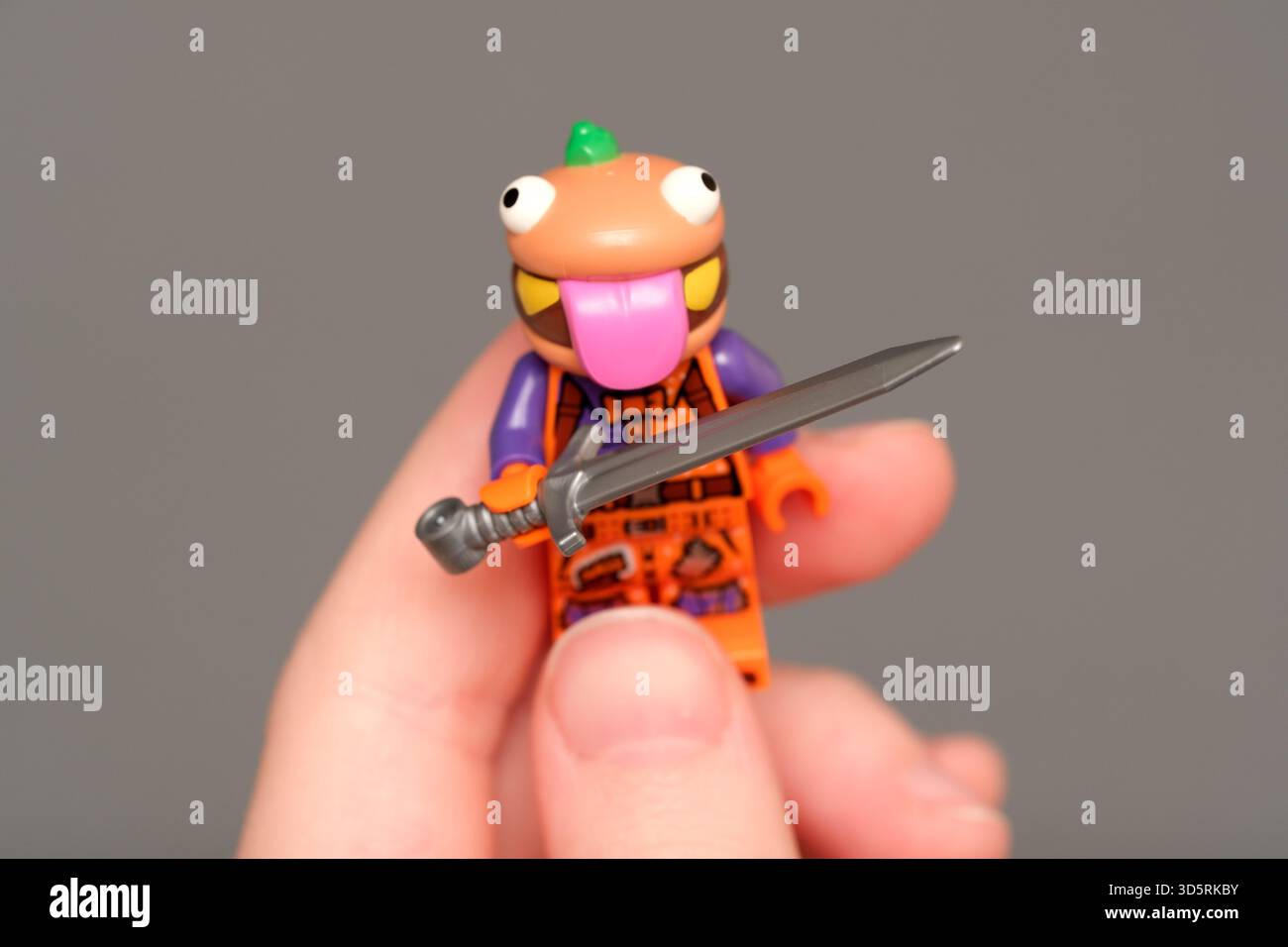 Eine fröhliche Spielzeugfigur hält ein Schwert und zeigt Kreativität und Verspieltheit in Aktion. Stockfoto