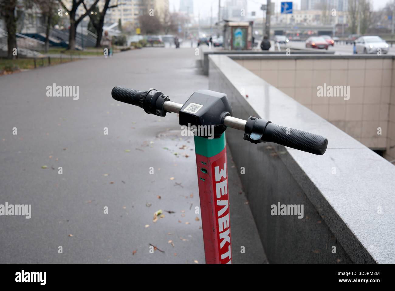 Ein lebendiger Elektroroller steht in einer ruhigen Kiewer Straße bereit, wenn die Herbstblätter fallen. Stockfoto