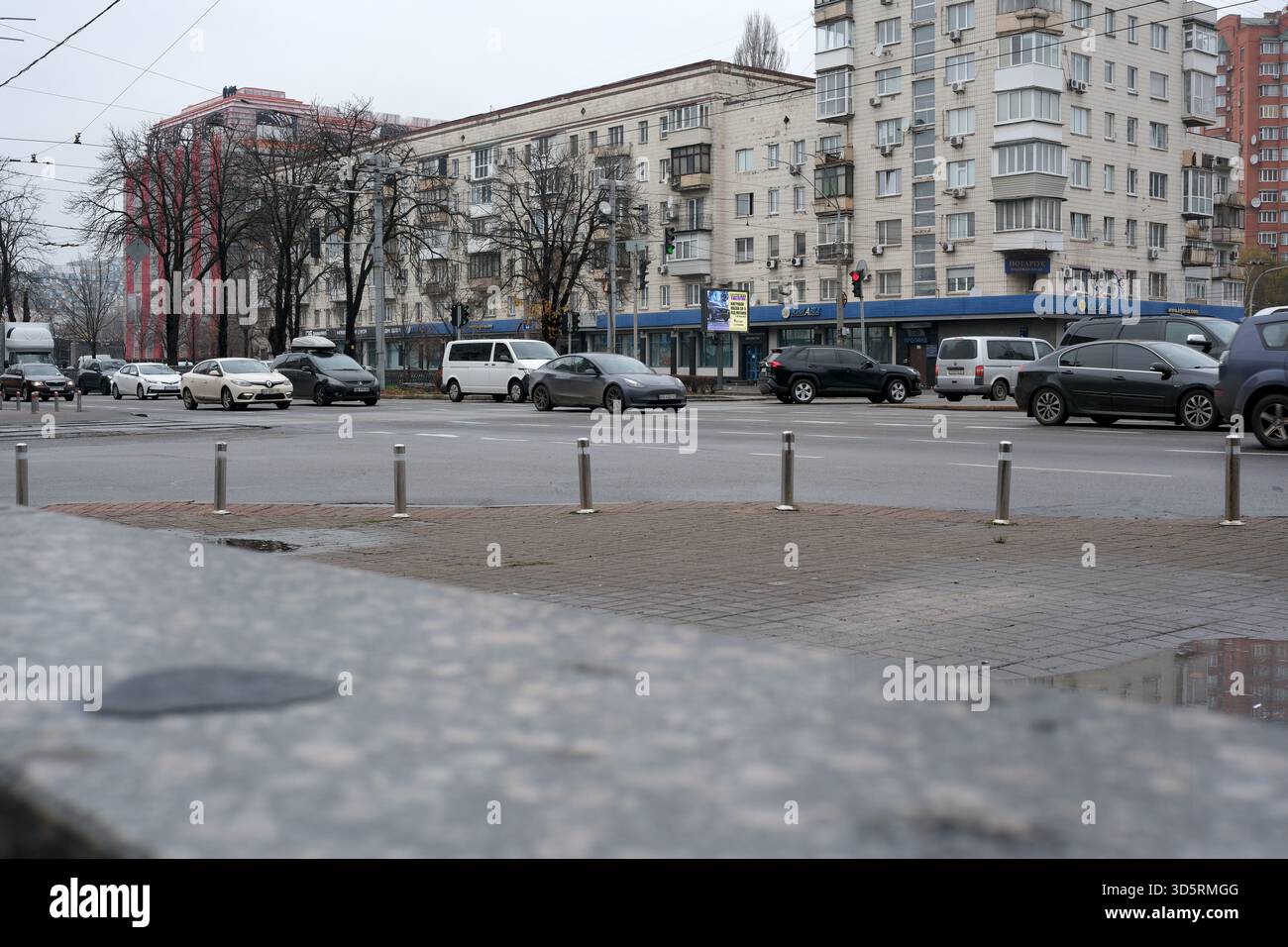 Ein grauer Himmel bedeckt Kiew an einem kühlen Novembertag, während Autos durch geschäftige Straßen fahren. Stockfoto