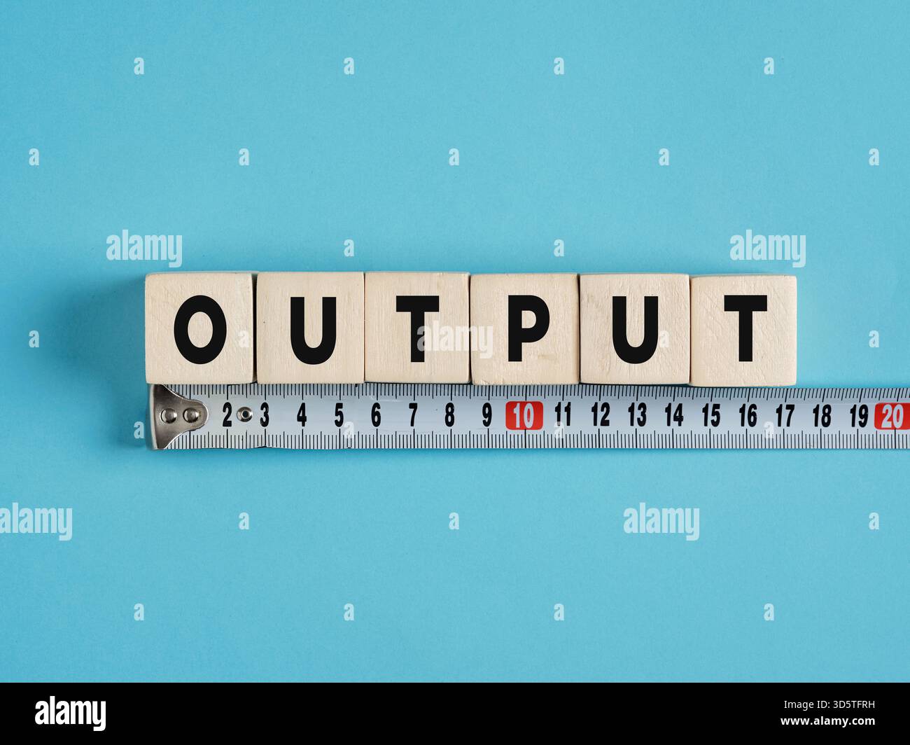 Holzwürfel, die die Wortausgabe bilden, werden mit einem Maßband gemessen, was die Leistungsbewertung und Effizienzanalyse symbolisiert Stockfoto