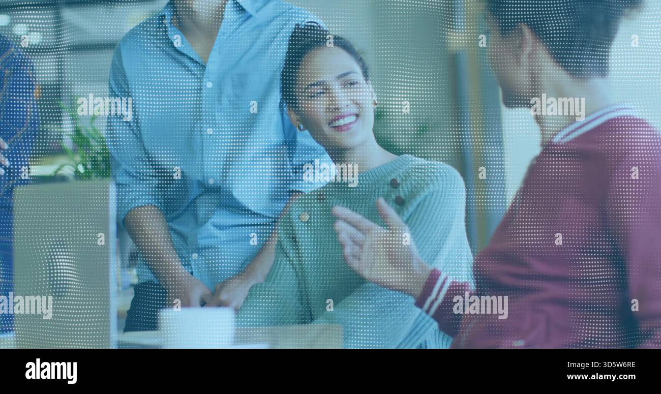 Lächelnde Frau in grünem Pullover, die Mann am Bürotisch hinter gepunktetem Glas ansieht, Kaffeetasse Stockfoto