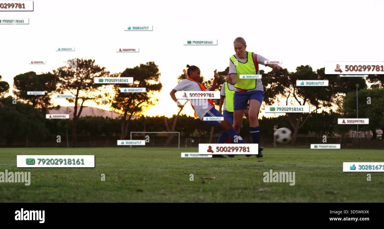 Spieler in Neonwesten, die gleiten, den Ball bei Sonnenuntergang auf dem Schulfeld mit ID-Etiketten steuern Stockfoto