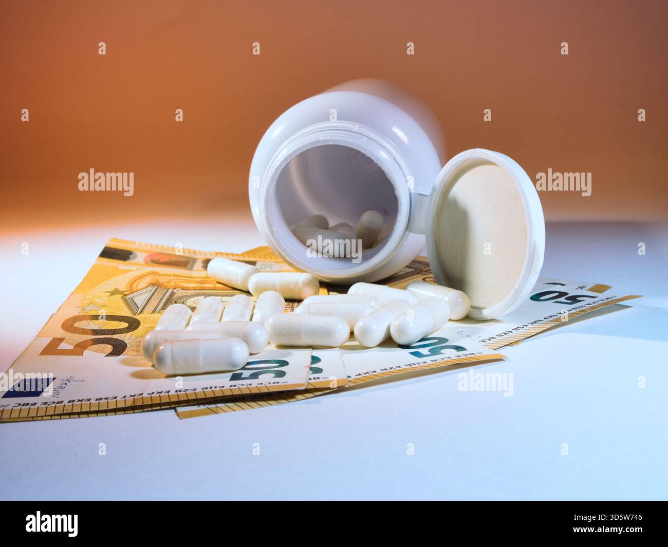 Hohe Kosten für Medizin in Euro - umgekippte weiße Pille-Flasche mit Kapseln auf mehreren 50-Euro-Banknoten, was die finanzielle Belastung unterstreicht Stockfoto
