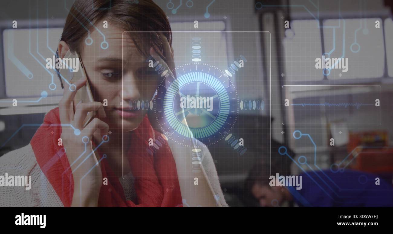 Telefonisch auf dem Smartphone, Frau mit rotem Schal und Strickpullover im Büro mit Monitoren, Holo HUD Stockfoto