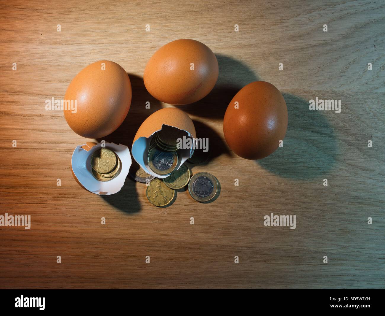 Nest Egg Savings – zerbrochene braune Eier zeigen Euro-Münzen auf einem Holztisch, die Finanzwachstum, versteckten Reichtum, Investitionen und ein sicheres Nest symbolisieren Stockfoto