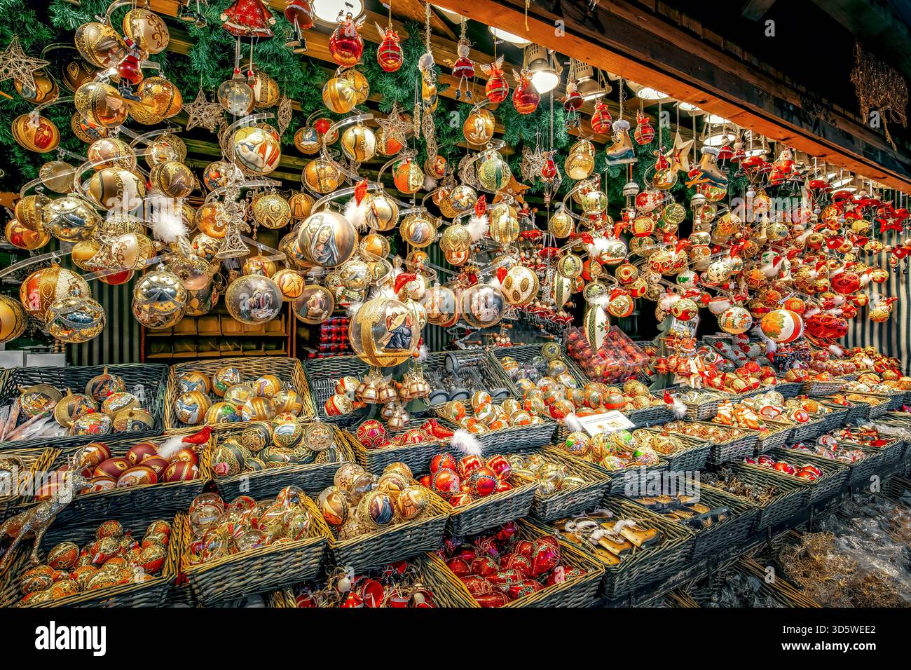 Goldene, rote und farbenfrohe Weihnachtsdekorationen hängen und füllen Korbkörbe und schaffen eine festliche Atmosphäre auf dem berühmten Wiener Weihnachtsmarkt. Stockfoto