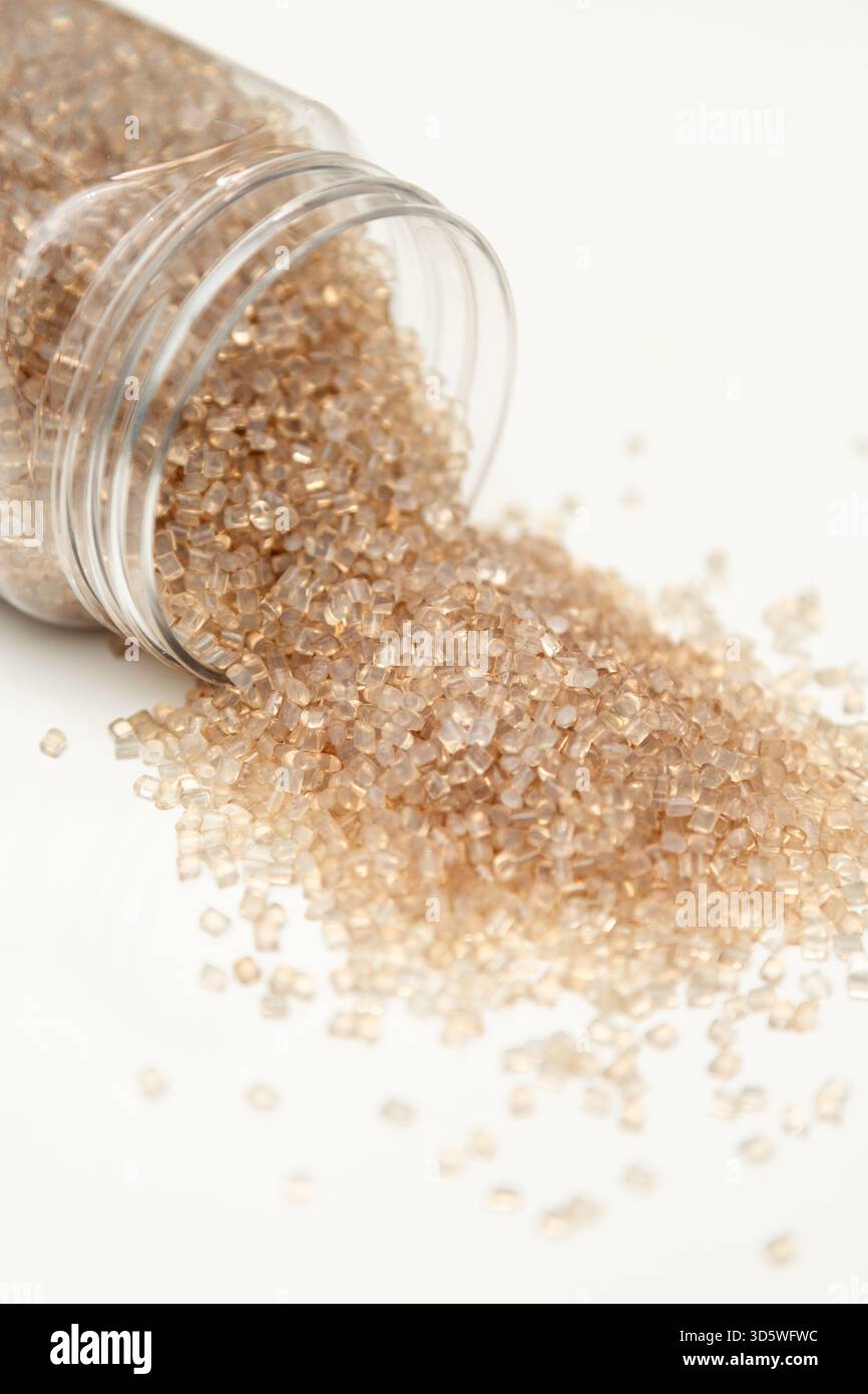 Klare Polymerpellets, die aus einem Kunststoffbehälter fließen Stockfoto