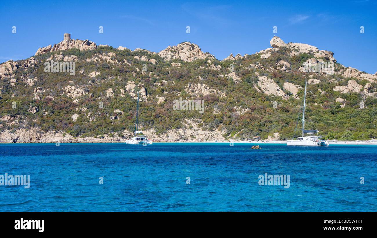 Die Bucht von Roccapina mit ihrem wunderschönen türkisfarbenen Wasser vom Meer aus gesehen, mit dem Wachturm und liegendem Löwen auf dem Hügel in der Sonne Stockfoto
