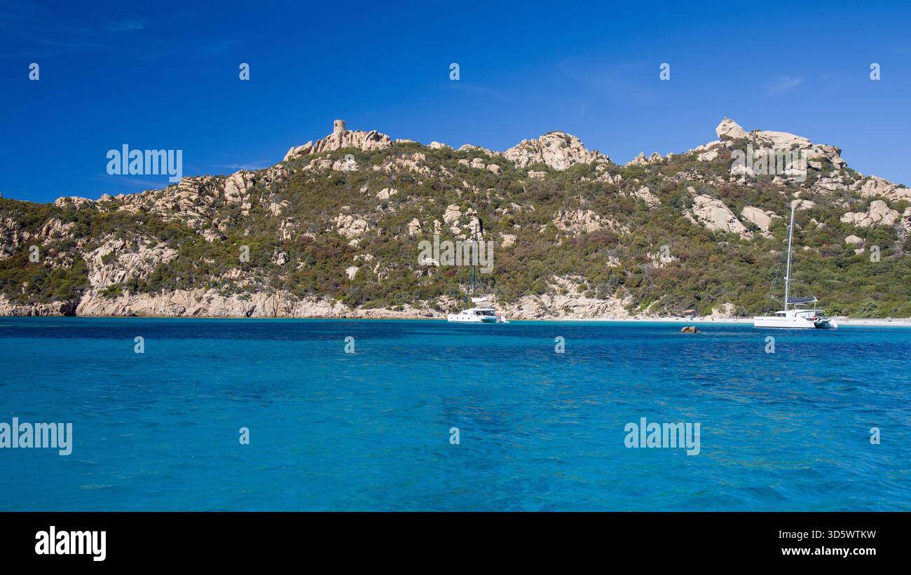 Die Bucht von Roccapina mit ihrem wunderschönen türkisfarbenen Wasser vom Meer aus gesehen, mit dem Wachturm und liegendem Löwen auf dem Hügel in der Sonne Stockfoto