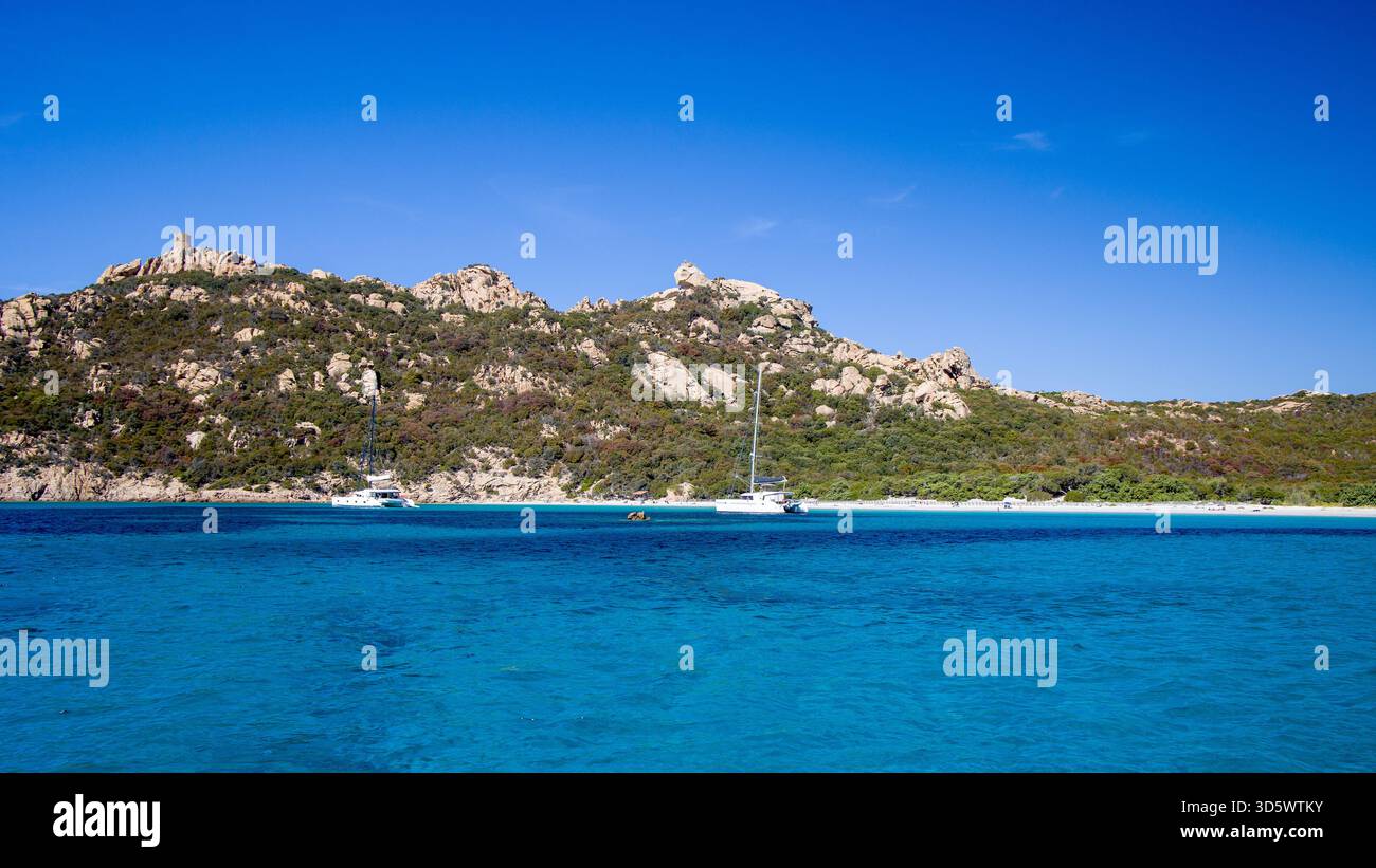 Die Bucht von Roccapina mit ihrem wunderschönen türkisfarbenen Wasser vom Meer aus gesehen, mit dem Wachturm und liegendem Löwen auf dem Hügel in der Sonne Stockfoto