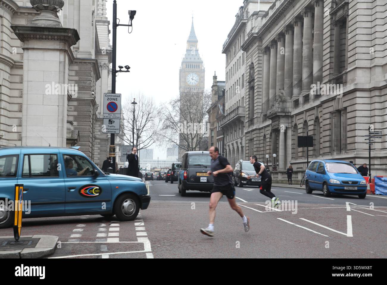 Die Hektik des Londoner Alltags. Jogger überqueren die Straße in der Nähe von One Great George am 2011. Februar mit dem Big Ben und dem schwarzen Taxi dahinter Stockfoto