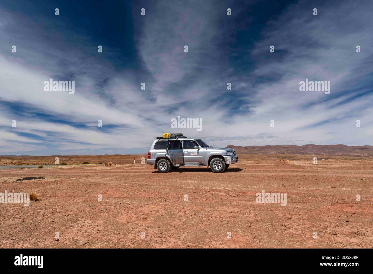 Geländewagen, der auf dem bolivianischen Altiplano unter einem dramatischen weiten Himmel geparkt ist Stockfoto