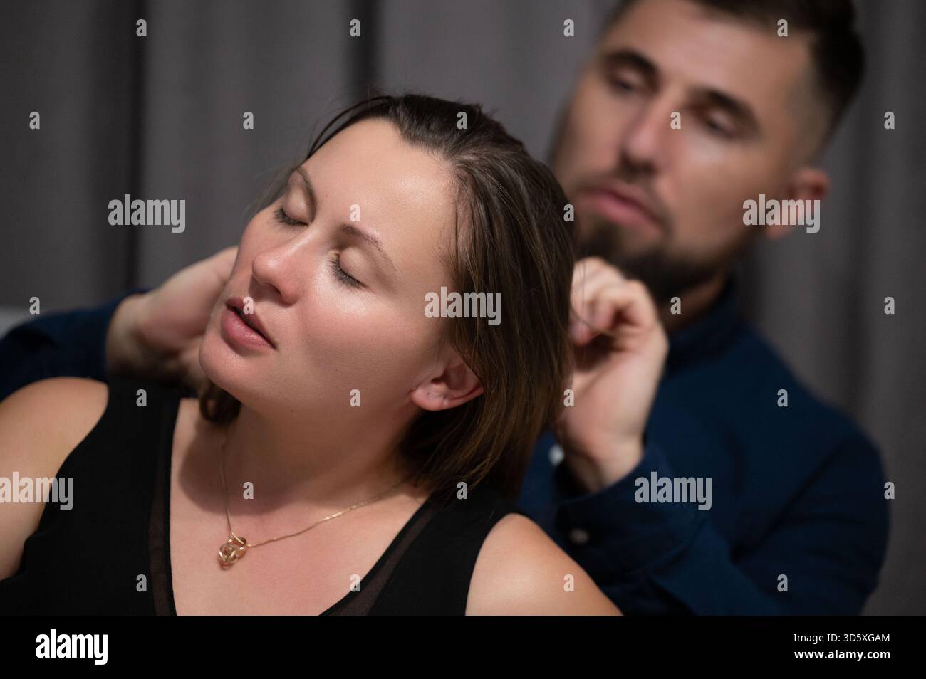 Warme, intime Momente der Freundschaft entfalten sich, während eine Person die Haare der anderen sorgfältig stylt, umgeben von sanfter Beleuchtung und einer ruhigen Atmosphäre in einer Co-Umgebung Stockfoto