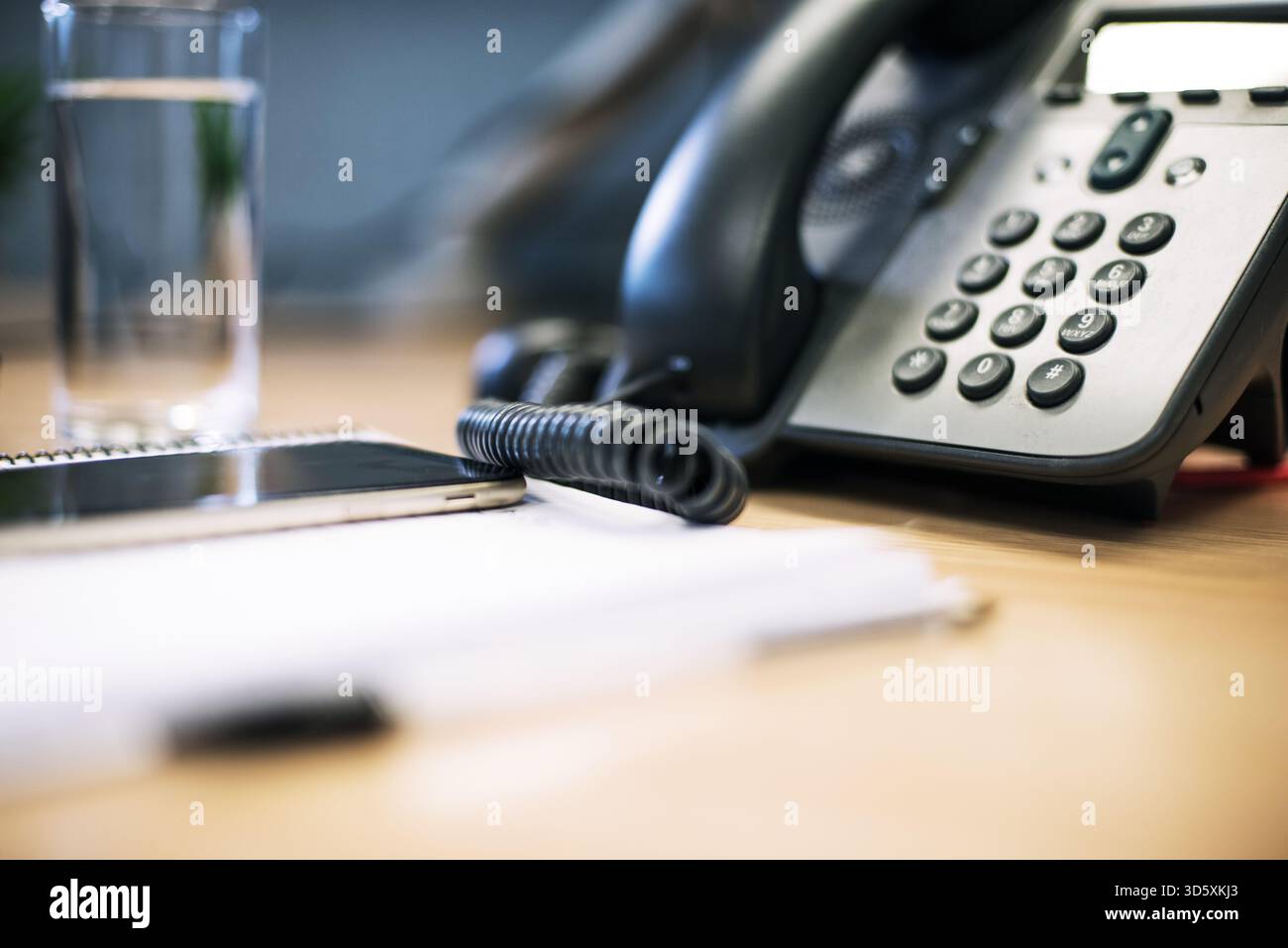 Telefon auf dem Schreibtisch mit einem Glas Wasser Stockfoto
