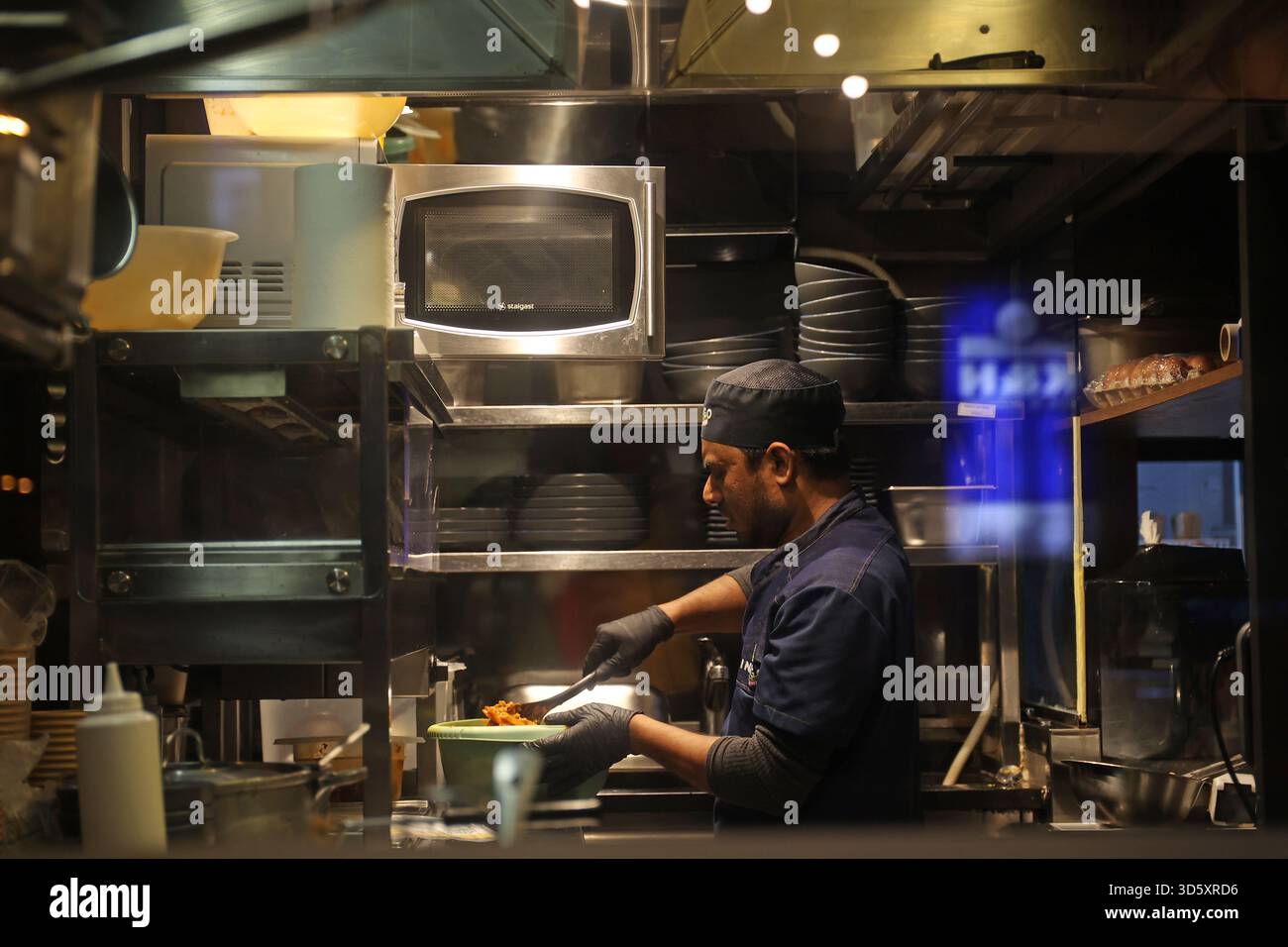 Küchenchef, der in der Küche eines indischen Street Food Restaurants in Budapest, Ungarn, Essen zubereitet Stockfoto