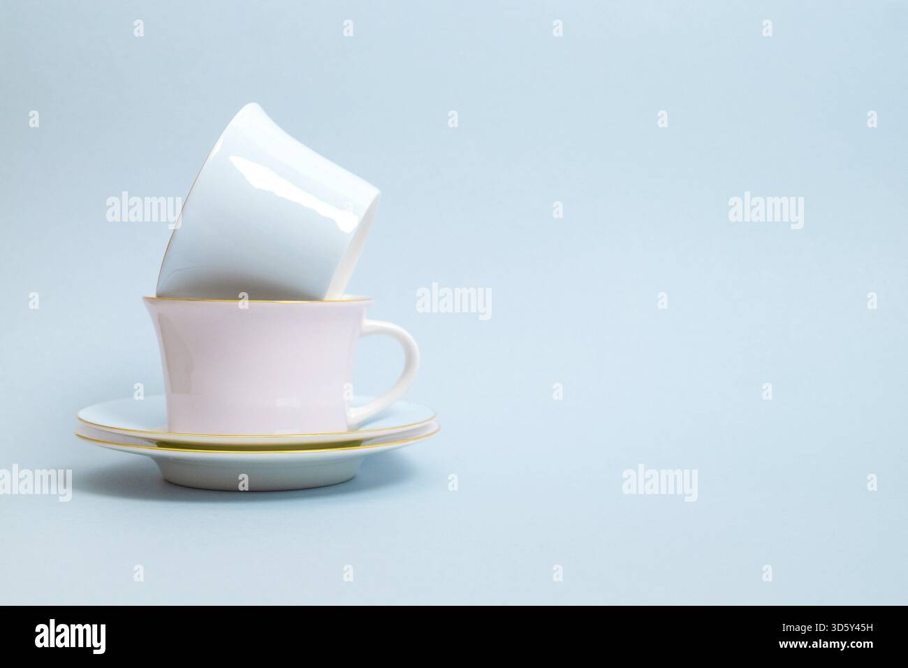 Zwei Porzellantassen und Untertassen für Tee oder Kaffee in blauen und rosa Farben stehen auf blauem Hintergrund. Pastellfarben. Selektiver Fokus. Kopierbereich Stockfoto