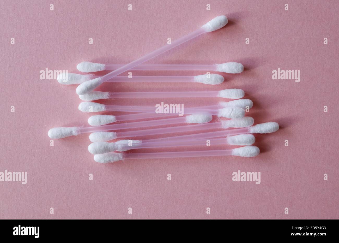 Baumwoll-Sticks für Hygiene und Make-up aus Kunststoff und natürlicher Baumwollfaser auf rosa Hintergrund. Kunststofffrei, Kosmetikkonzept. Nahaufnahme. Ansicht Stockfoto