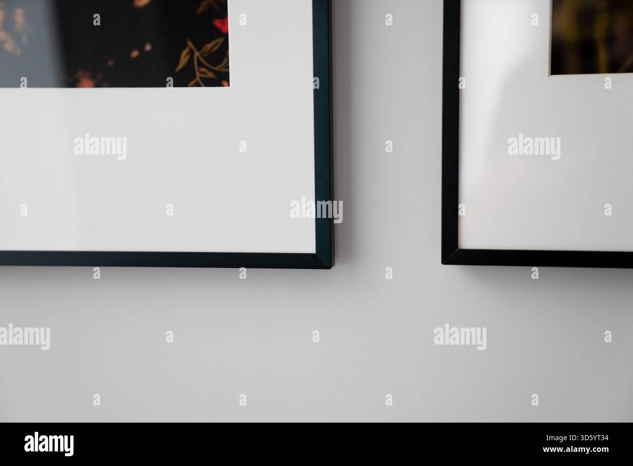 Moderne Inneneinrichtung mit schwarzen Bilderrahmen auf glatter Wandfläche, die klare Ästhetik, strukturiertes Layout und raffiniertes Dekor betonen Stockfoto