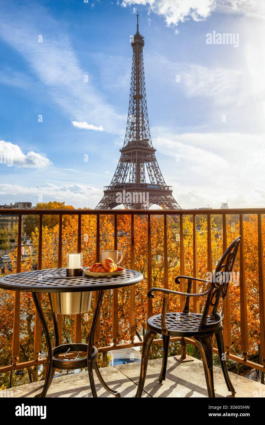 Ein Balkon mit Frühstückstisch und leerem Stuhl mit Blick auf den Eiffelturm in Paris, Frankreich, während der Morgenzeit und bei Sonnenschein Stockfoto