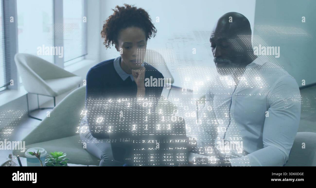 Kollegen, die in der Lounge an einem Laptop arbeiten, einen dunklen Pullover, ein weißes Hemd des Mannes, die Binärüberzüge sehen Stockfoto