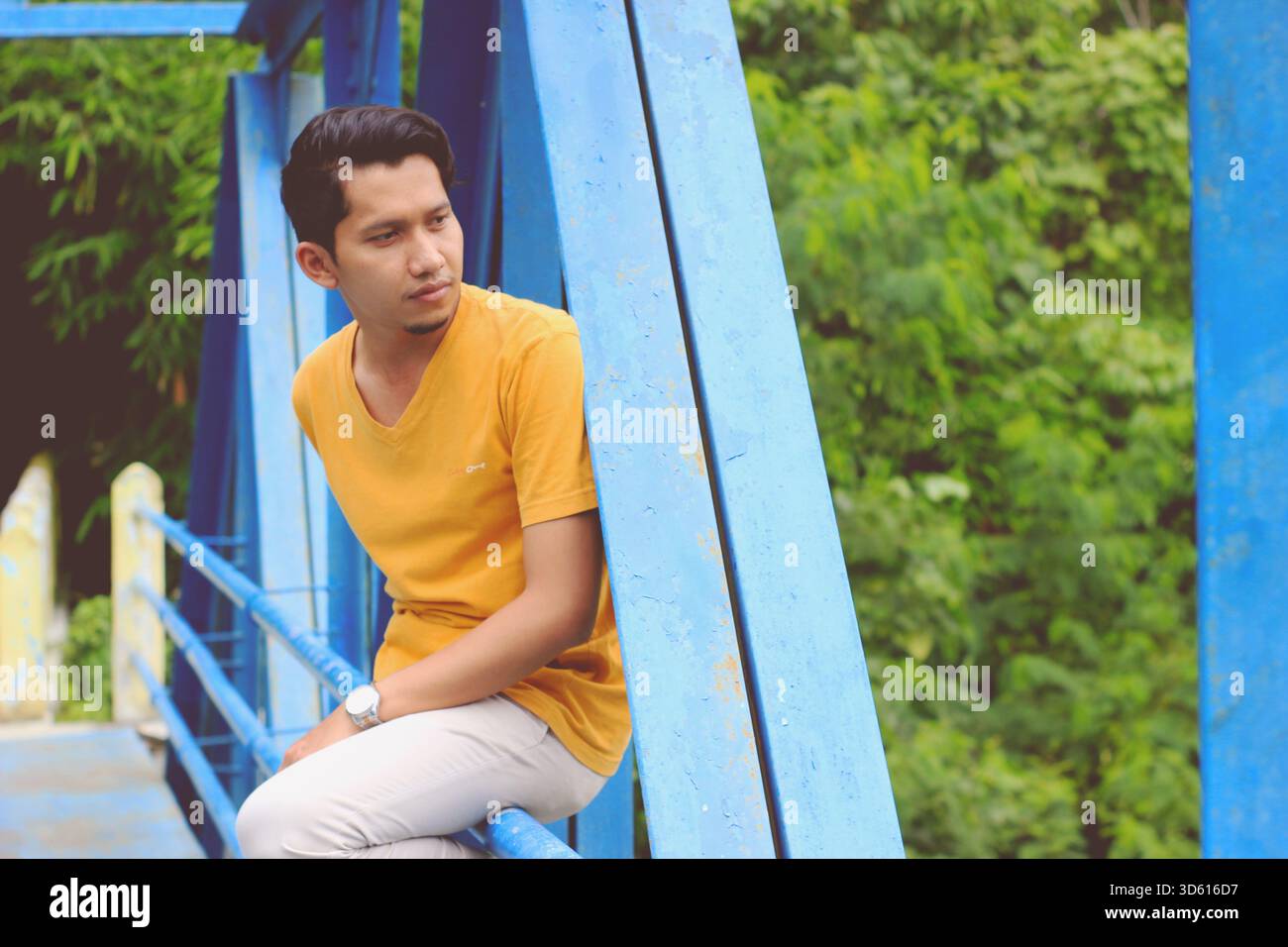 Ein Tourist posiert mit einer Brücke im Hintergrund Stockfoto