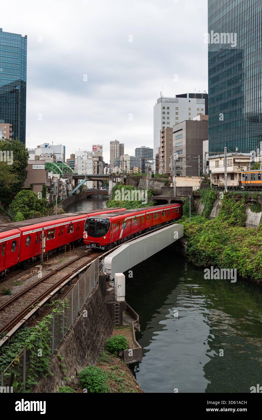 Die legendären roten Züge der Tokyo Metro Marunouchi Line steigen aus einem Tunnel auf und überqueren den Kanda River auf einer Brücke im Zentrum von Tokio. Stockfoto