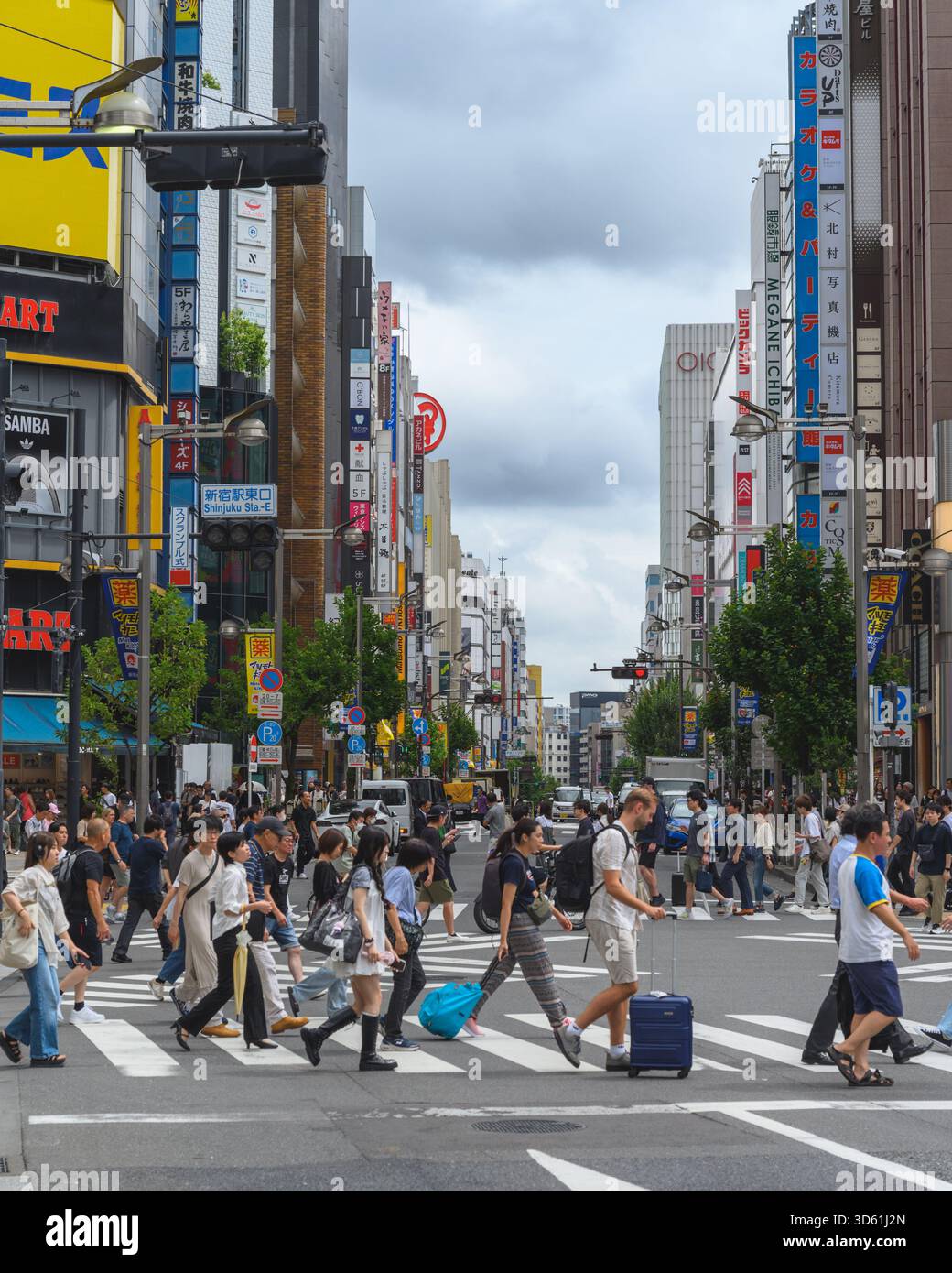 Eine Straßenaufnahme einer Menschenmenge von Fußgängern, die eine geschäftige Kreuzung im Stadtteil Shinjuku in Tokio überqueren. Stockfoto