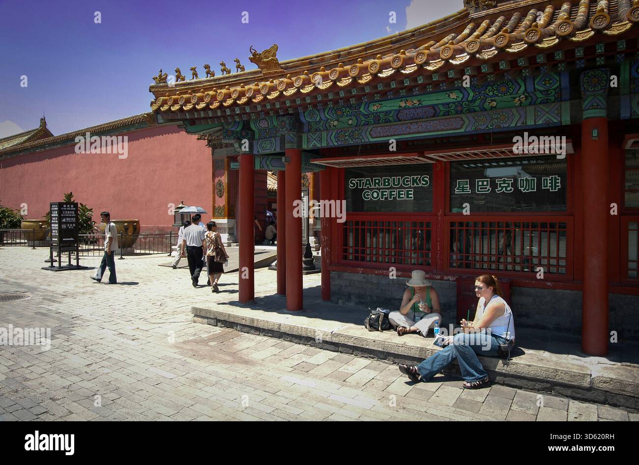 Verbotene Stadt, Starbucks Kaffee, Peking, China. Juli 2004. Touristen mit Getränken vor dem Starbucks Coffee Shop in der Nähe der Hall of Conservving Harmony in der Verbotenen Stadt in der chinesischen Hauptstadt Peking. Der kleine Coffee Shop wurde 2000 eröffnet und 2007 geschlossen, nachdem Proteste, dass er unangemessen sei oder die historische Kulturstätte beschädigte. 2007 nannte Howard Schultz, damals Chairman der Starbucks Corp. China den größten Wachstumsmarkt des Unternehmens. Stockfoto