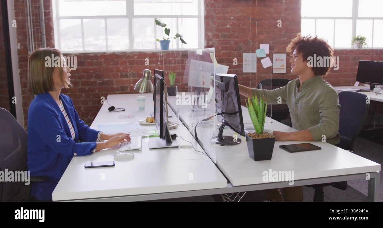 Eine asiatische Frau mit königsblauem Blazer, hellgrünem männlichem Hemd, die eine Haftnotiz an der Trennwand des Büros platziert Stockfoto