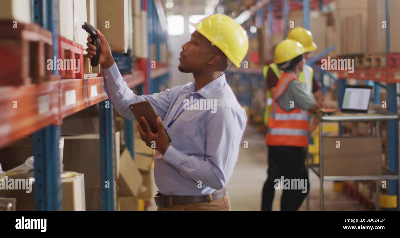 Inspektionsleiter im Lager trägt gelbe Schutzhelme mit Barcode-Scanner und Tablet Stockfoto