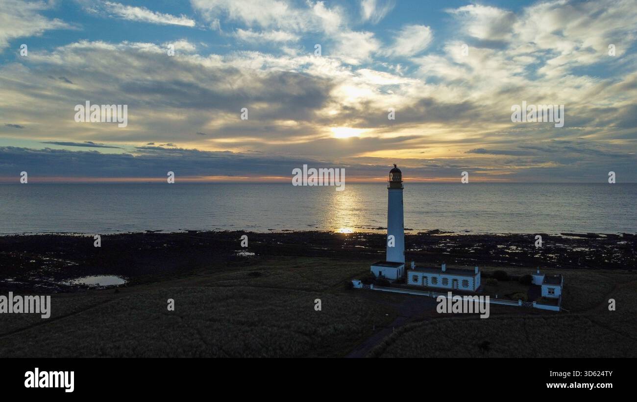Weite Luftaufnahme des Leuchtturms Barns Ness an der Küste von East Lothian mit der aufgehenden Sonne, die Licht über die Nordsee wirft Stockfoto