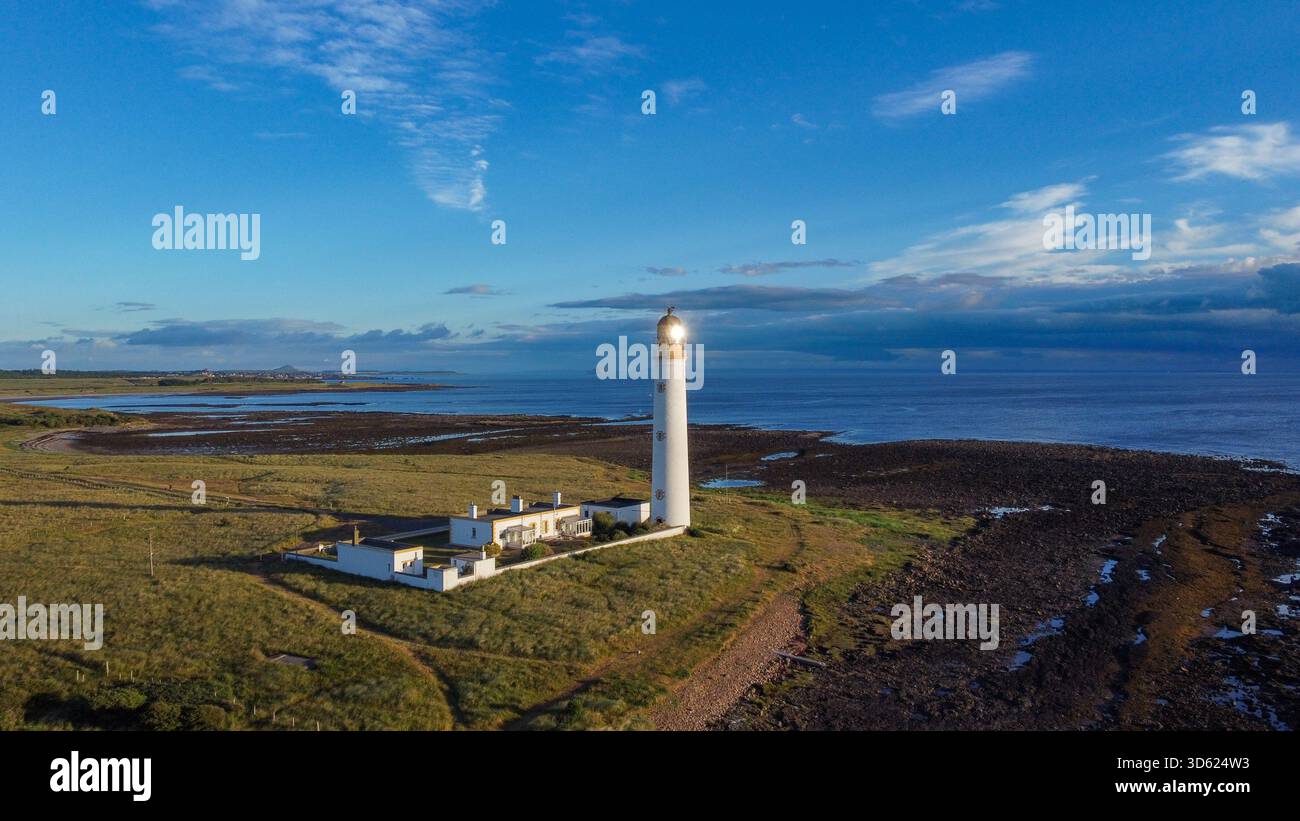 Weite Aussicht aus der Vogelperspektive auf den Leuchtturm von Barns Ness und die Hütten der Hüter an der felsigen und grasbewachsenen Küste der East Lothian Küste Stockfoto
