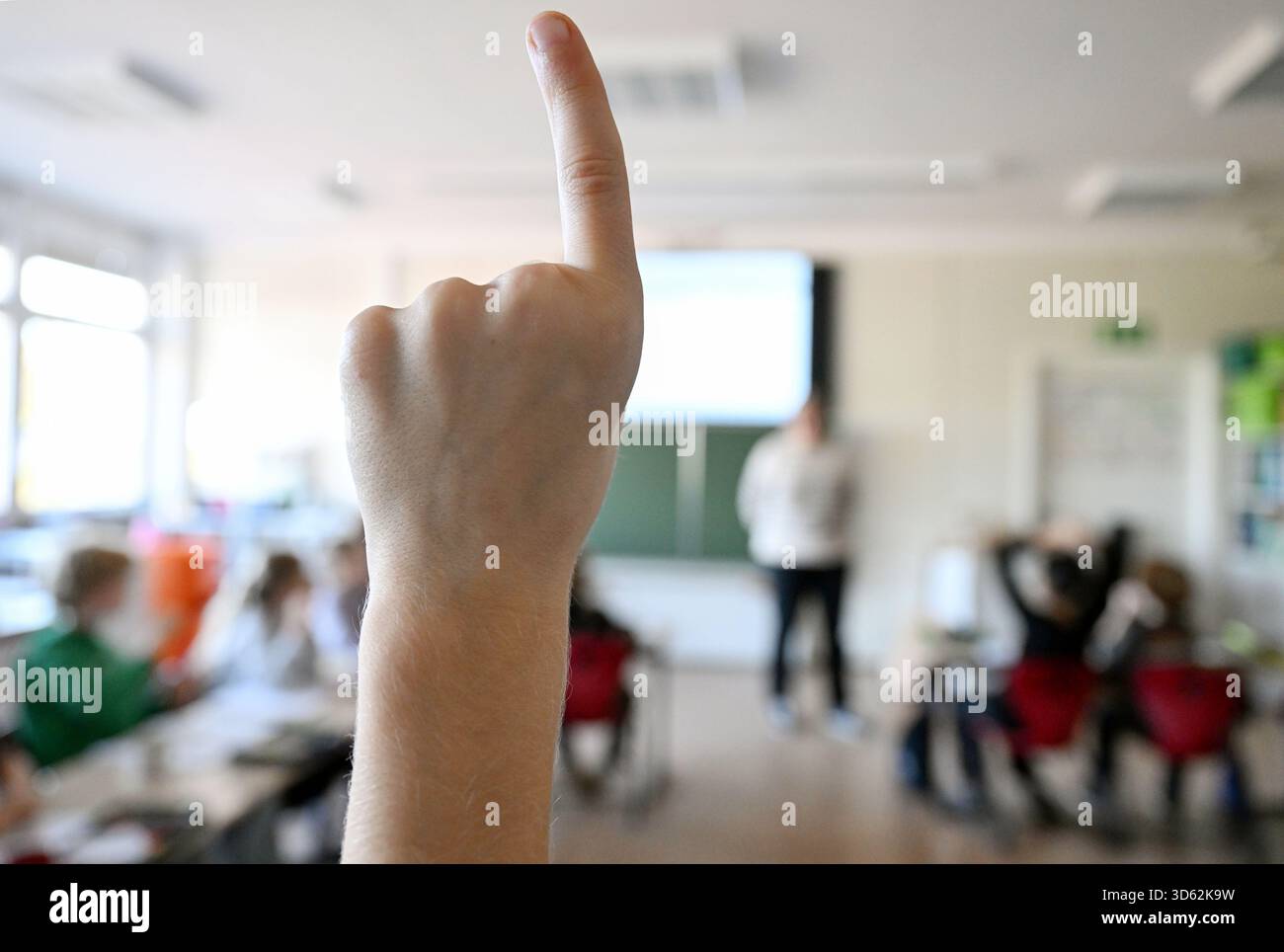 SYMBOL - 05. November 2025, Baden-Württemberg, Stuttgart: Ein Schüler der vierten Klasse meldet sich in der Mathematikklasse an einer Grundschule, während der Lehrer an der Vorderseite des Klassenzimmers auf einem digitalen Whiteboard unterrichtet. Foto: Bernd Weißbrod/dpa Stockfoto