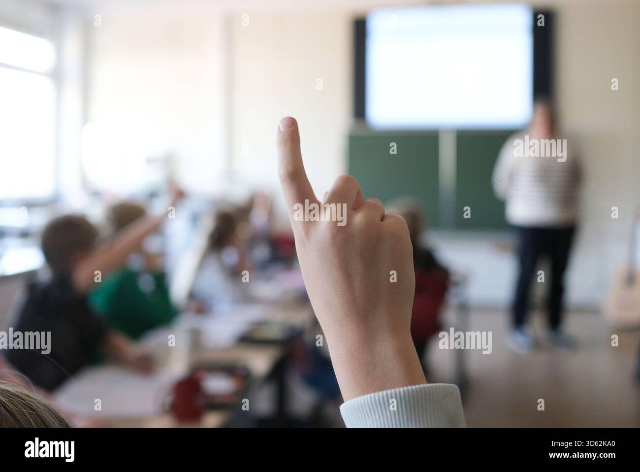 SYMBOL - 05. November 2025, Baden-Württemberg, Stuttgart: Ein Schüler der vierten Klasse meldet sich in der Mathematikklasse an einer Grundschule, während der Lehrer an der Vorderseite des Klassenzimmers auf einem digitalen Whiteboard unterrichtet. Foto: Bernd Weißbrod/dpa Stockfoto