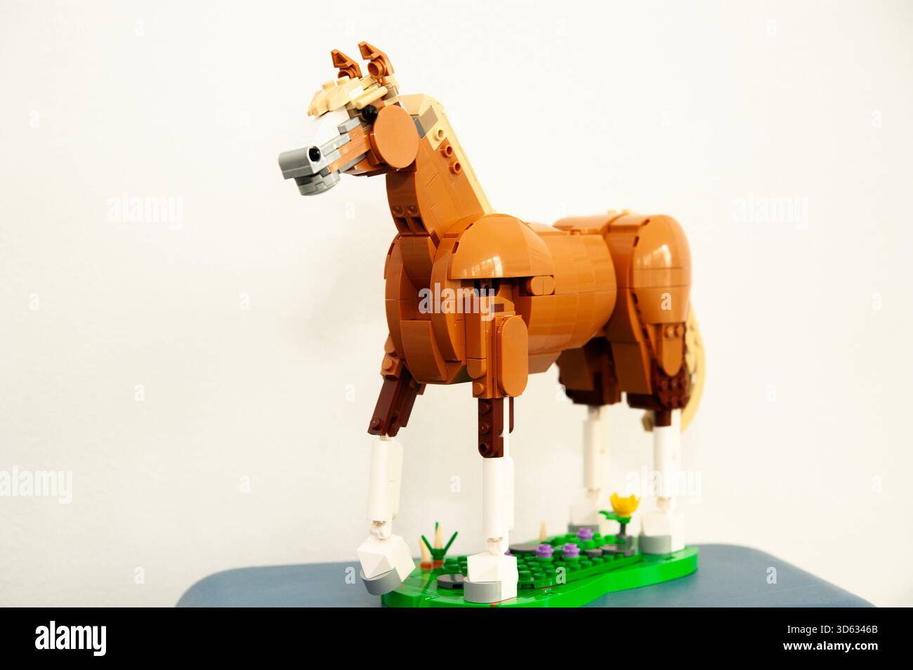 Eine detaillierte LEGO-Pferdeskulptur aus braunen und braunen Plastikziegeln, die auf einem kleinen grünen Sockel steht Stockfoto