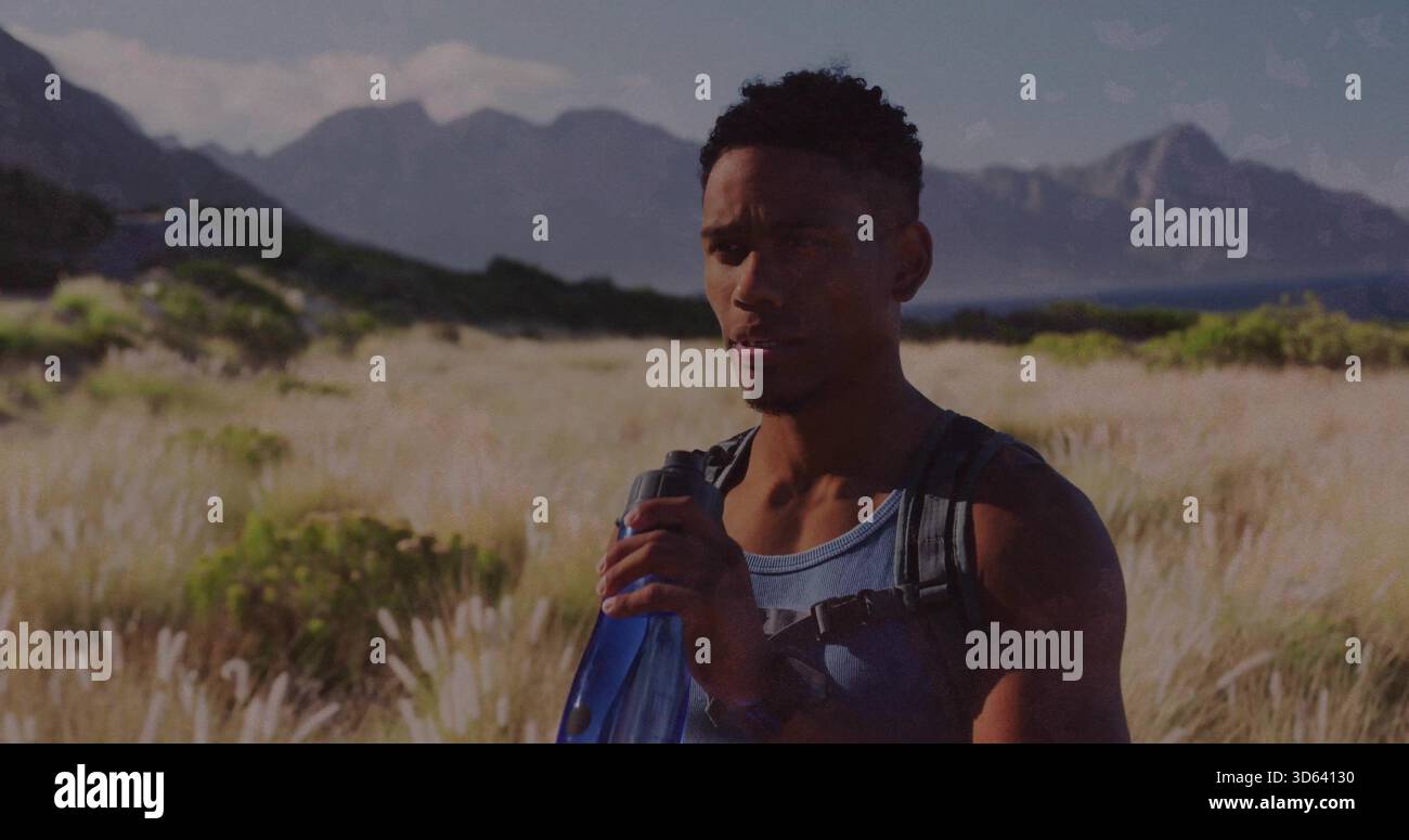 Schlürft Mann, der auf der Landwiese inne hält, blaue Flasche hält, blaues Tanktop und schwarzen Rucksack trägt Stockfoto