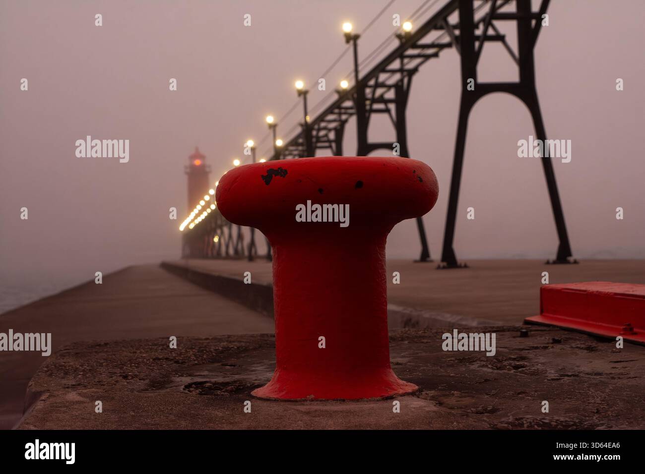 Sonnenaufgang an einem nebeligen Morgen auf dem Grand Haven South Pierhead mit dem inneren Leuchtfeuer und dem äußeren Leuchtturm. Stockfoto