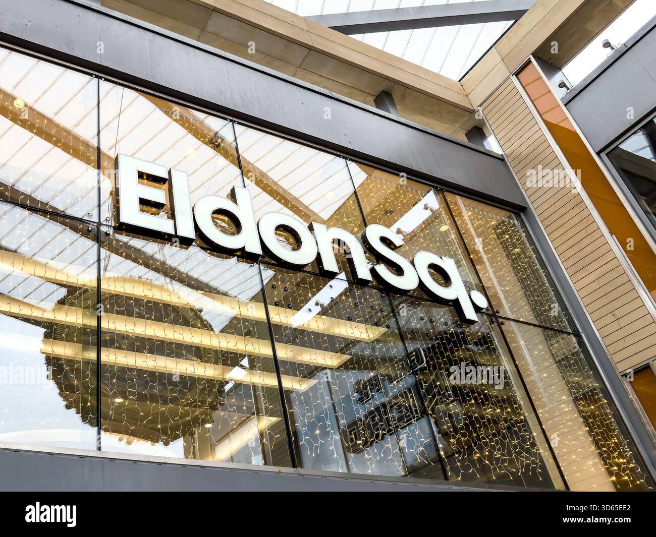 Moderne Glasfassade des Eldon Square Shopping Centre, Newcastle mit sichtbaren Reflexen und dekorativen hängenden weihnachtslichtern - Smartphone-aufgenommenes Stockfoto
