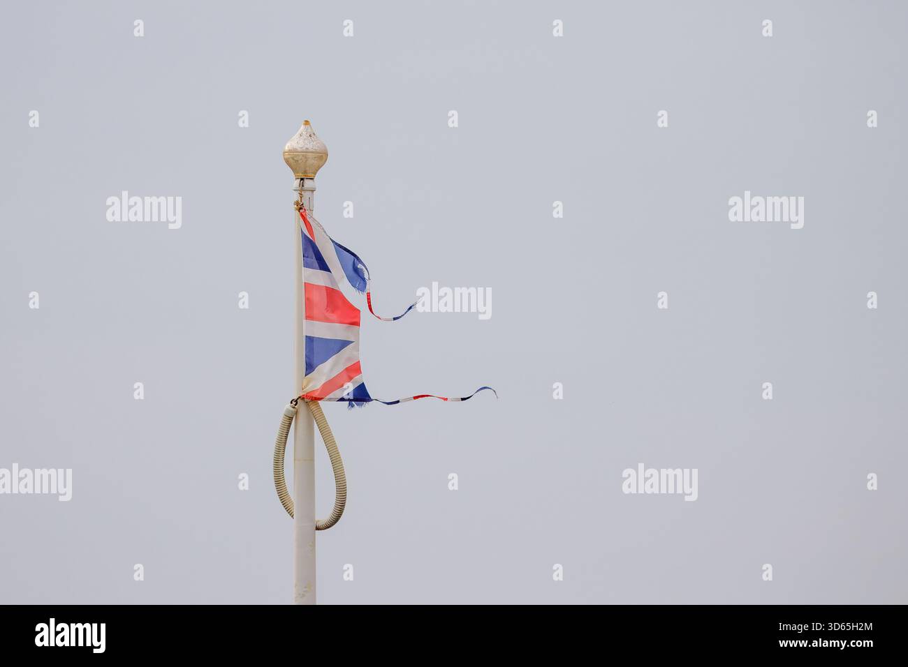Symbolisch zerrissene Union Jack gegen den bewölkten Himmel. Stockfoto