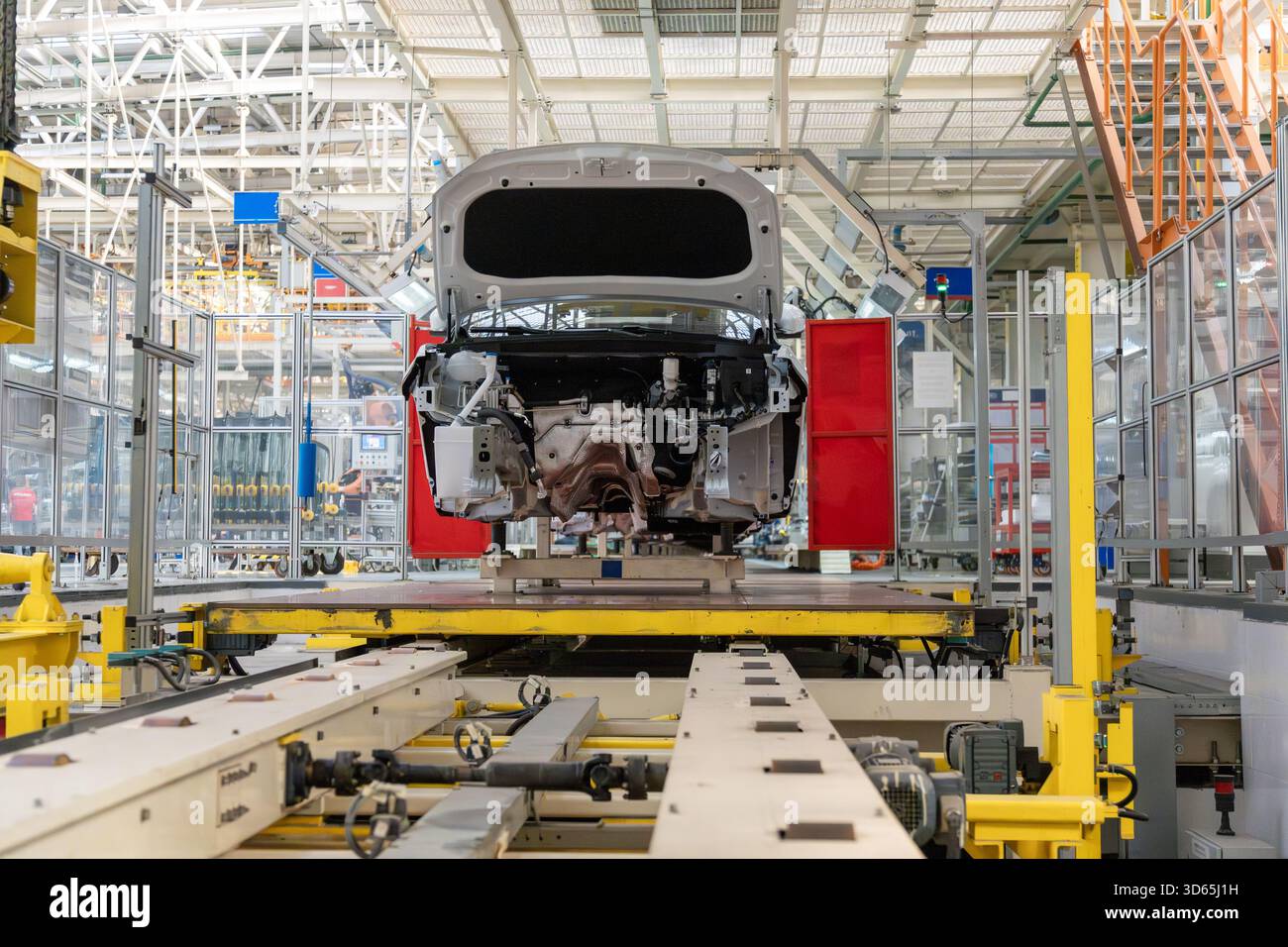 Eine moderne High-Tech-Kfz-Montagelinie mit einem weißen Fahrgestell, montiert auf einem gelben Fördersystem in einer industriellen Fabrik während Stockfoto