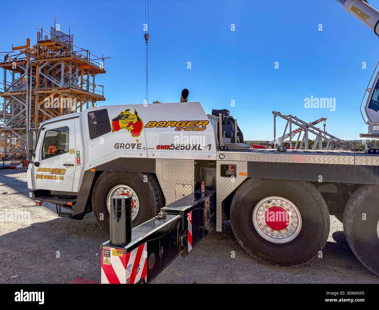 Mobiler Radbaukran mit ausgefahrenen Stützauslegern auf einer Baustelle in Sydney, Australien, arbeitet der Kran schwergängig - Smartphone-aufgenommenes Stockfoto