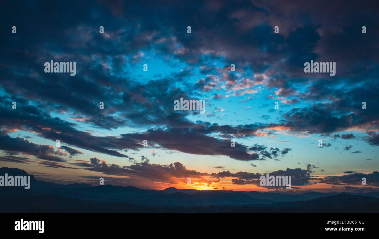 Abstrakte Landschaft mit einem surrealen leuchtend blauen Himmel und dramatischen Wolkenformationen, ideal für redaktionelle und kommerzielle Zwecke. Stockfoto