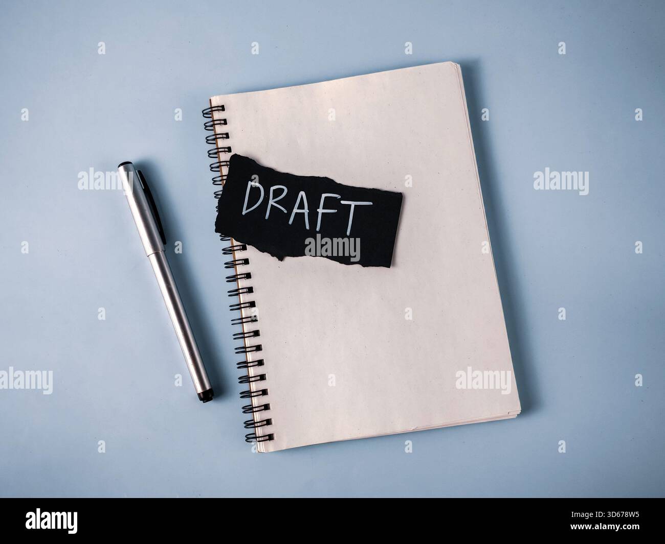 Entwurf eines Dokumentkonzepts: Notizbuch, Silberstift und Schwarzes Papier mit weißem „Entwurfstext“ zum Schreiben und Überarbeiten Stockfoto